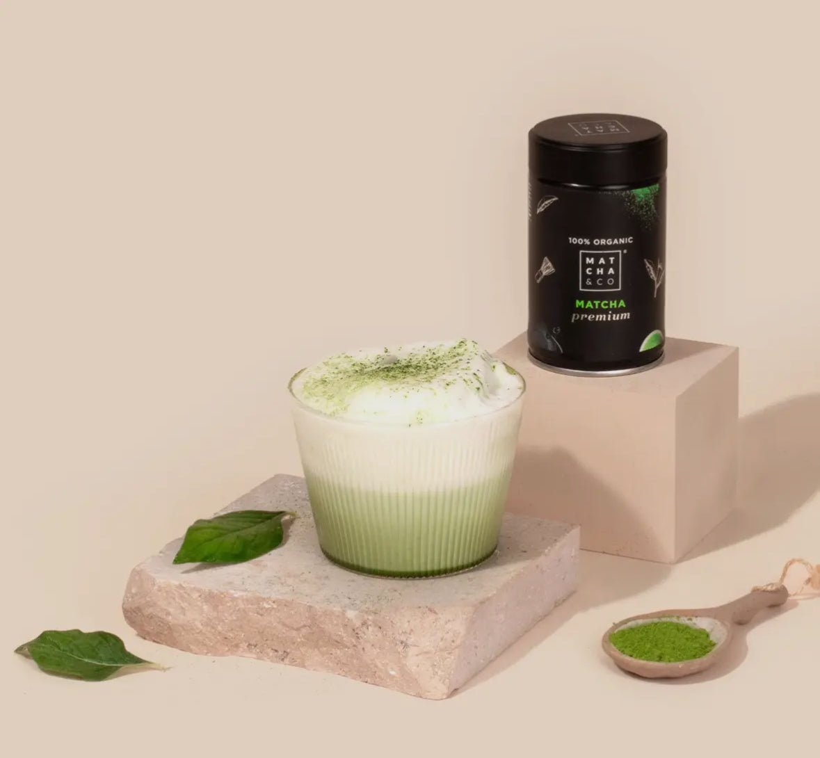 Bio matcha natuurlijk premium matcha powder with a frothy green matcha latte and fresh leaves