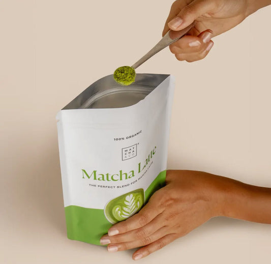 MatchaGirls package with green matcha powder being scooped for matcha latte met kokosmelk preparation
