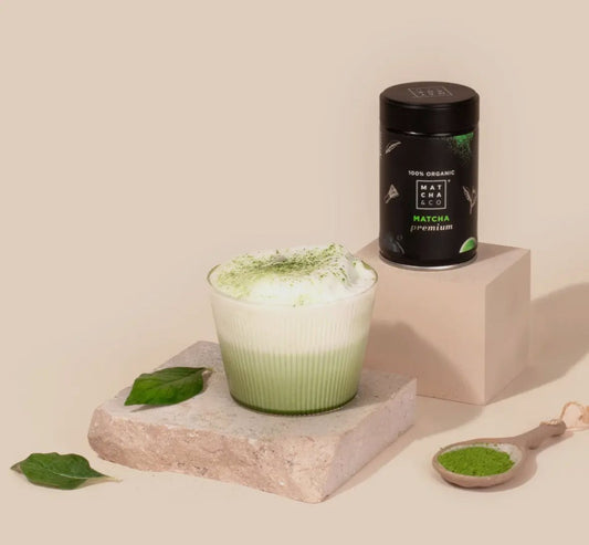 Bio matcha natuurlijk premium matcha powder with a frothy green matcha latte and fresh leaves